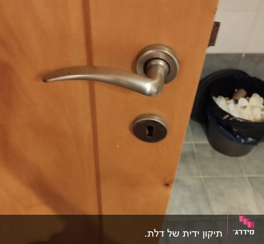 ידית דלת מתכתית ומנעול על דלת עץ